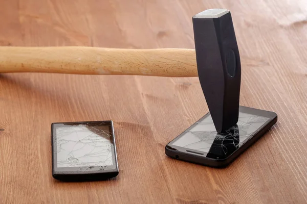 the hammer broke the screens of two smartphones on a wooden table. family disconnection from mobile slavery