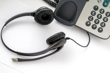 Geleneksel bir çağrı merkezi çalışanı için kulaklık düğmesine basılı telefon, hafif arka plan