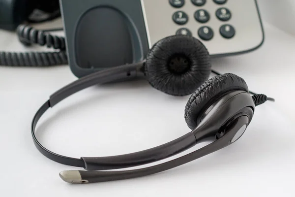 コールセンターの従業員の職場 伝統的なプッシュボタン電話とヘッドセット ヘッドフォンのクローズアップ — ストック写真