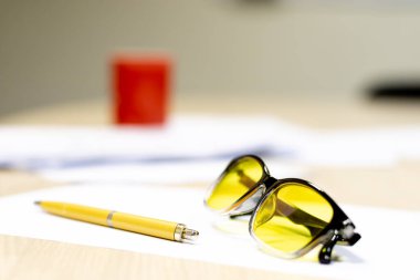 Sarı dolmakalem ve gözlükler beyaz bir masada sarı görüş için. yazar çalışma akışı