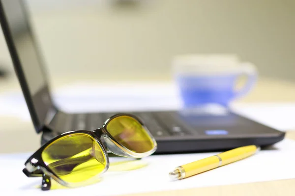 office worker tools laptop and ballpoint with glasses for working on a computer. eye wear safety glasses