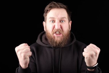 Dişlerini sıkıp yumruklarını sıkan sakallı huysuz, kızgın bir adam. Herkese kızgın.