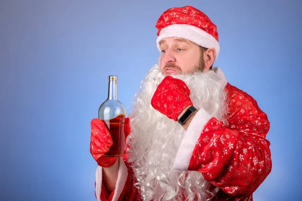 サンタのスーツの男が酒を飲むために嘘のひげをむいた 休日の前に酒を飲んで ストック写真
