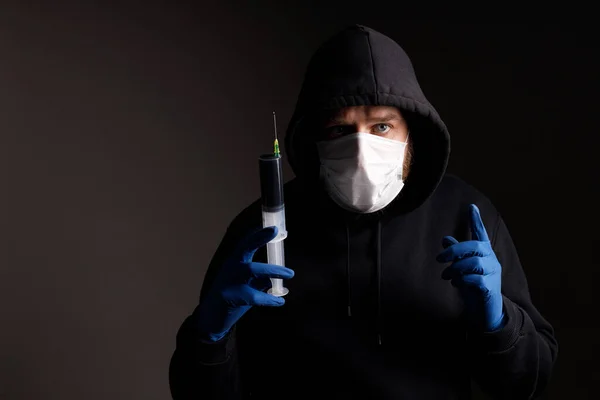 의료용 마스크와 고무장갑을 백인이 어두운 배경에 액체가 커다란 주사기를 위험을 — 스톡 사진