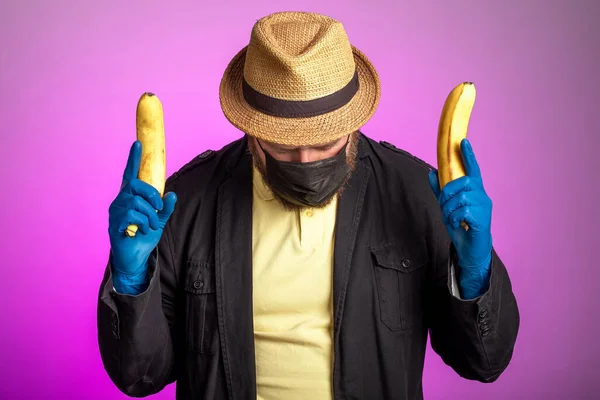 Человек Маске Шляпе Держит Бананы Обеих Руках Оружие Ирония Ношении — стоковое фото