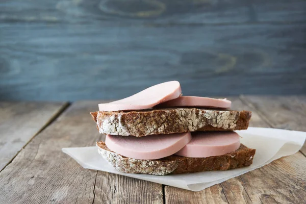 Haşlanmış sosis ve ahşap bir masa üzerinde çavdar ekmeği sandviç                   