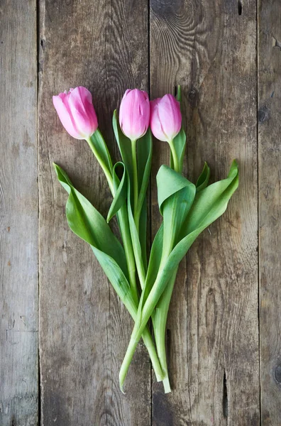 Ahşap bir masa üzerinde üç pembe laleler                               