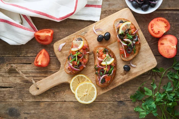 Bruschetta Con Tomate Aceitunas Cebolla Roja Una Tabla Cortar Madera —  Fotos de Stock