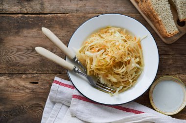 Ahşap bir masa üzerinde bir kapta soğan ile lahana turşusu                               