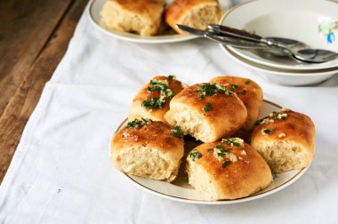 Bir plaka üzerinde sarımsak ve taze otlar ile ev yapımı çörekler                               