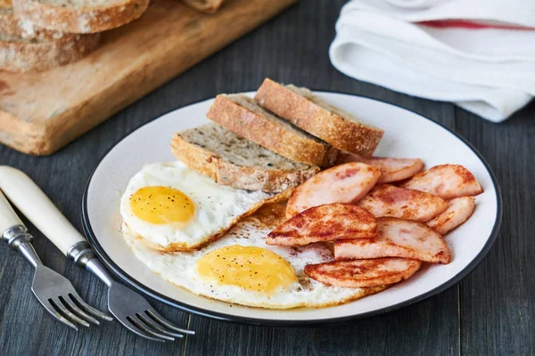 Fried eggs with chicken ham and bread on a plate