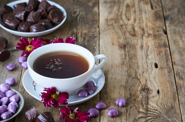 Una Taza Negro Con Caramelos Flores Una Mesa Madera — Foto de Stock