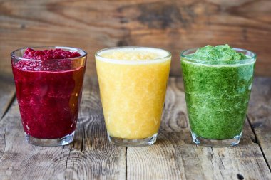 Ahşap masada pancar, salatalık ve turuncu renkli Smoothie 'ler                               