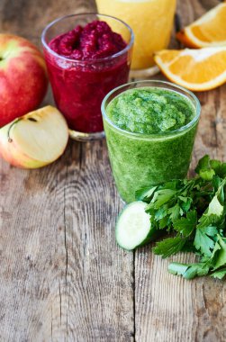 Ahşap masada pancar, salatalık ve turuncu renkli Smoothie 'ler                               