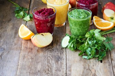 Ahşap masada pancar, salatalık ve turuncu renkli Smoothie 'ler                               