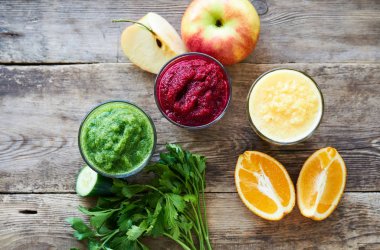 Ahşap masada pancar, salatalık ve turuncu renkli Smoothie 'ler                               