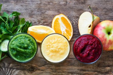 Ahşap masada pancar, salatalık ve turuncu renkli Smoothie 'ler                               