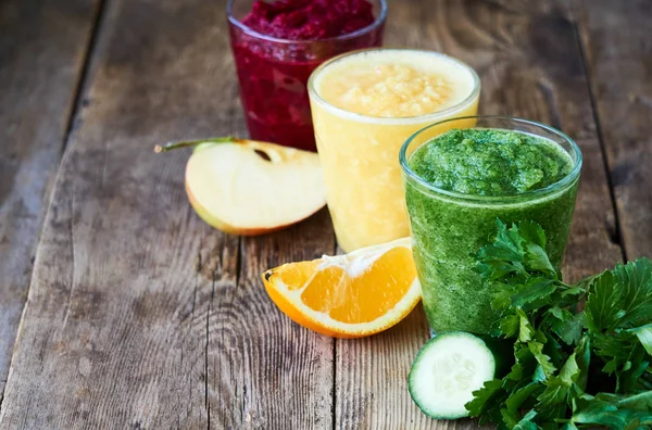 Colorful smoothies with beet, cucumber and orange on a wooden table