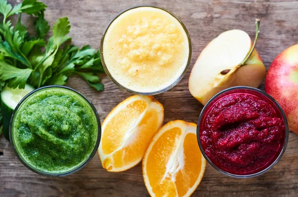 Colorful smoothies with beet, cucumber and orange on a wooden table
