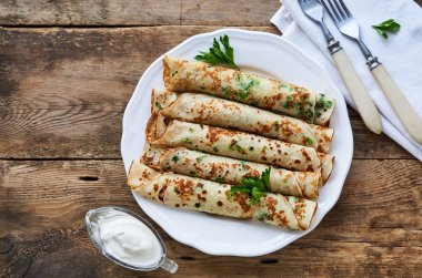 Bir tabakta taze yeşil soğan ve maydanoz ile Rus krep                               