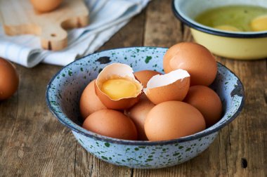 Ahşap bir arka plan üzerinde metal bir kapta Çiğ tavuk yumurtası                               