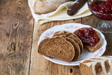 Ahşap bir masada erik reçeli ile çavdar ekmeği dilimleri                               