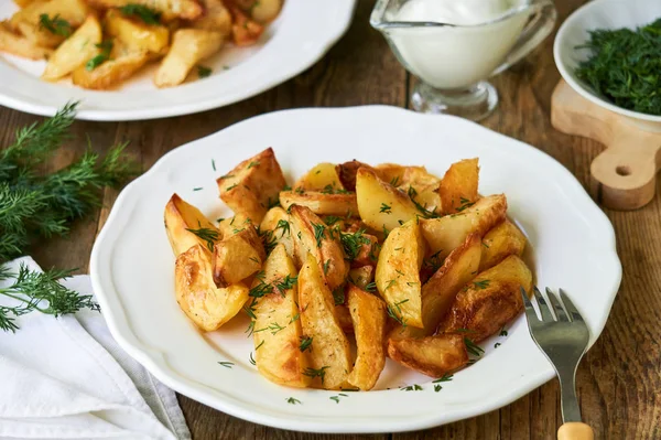 Baked potato slices with fresh dill on a white plate