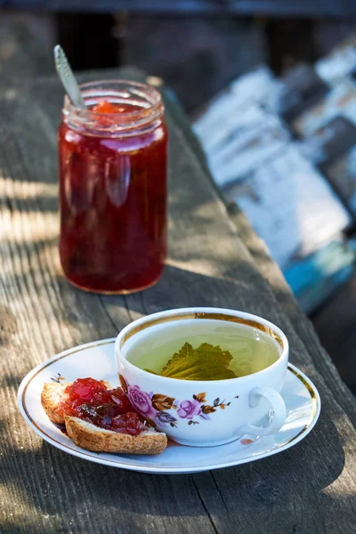 Eine Tasse Kräutertee Und Pflaumenmarmelade Sandwich Auf Einem Holztisch — Stockfoto