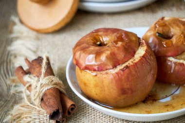 Beyaz bir tabakta bal ve tarçın ile pişmiş elma                               