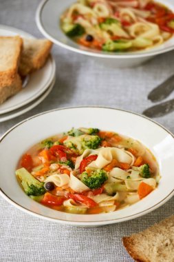 Beyaz bir kapta taze sebze ve erişte ile Çorba                                