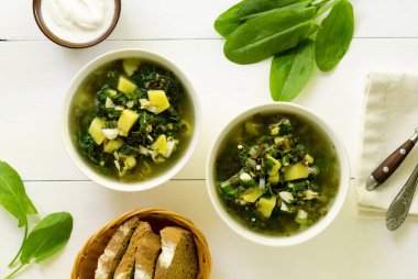 Beyaz arkaplanda patates ve atarlı yeşil çorba.