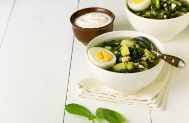 Yeşil sebze çorbası. Beyaz kâse içinde kuş yaprakları ve yumurtalar.