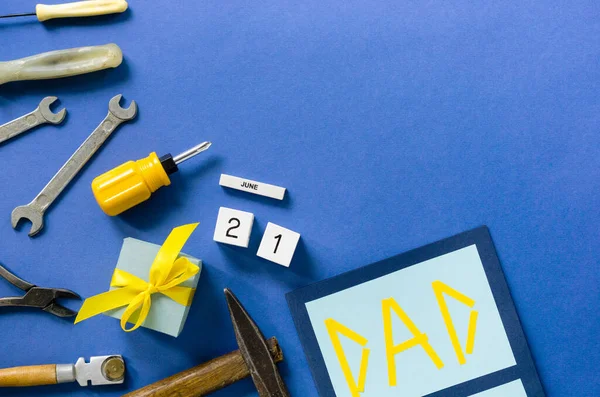 Flat lay for father's day with tools and gift box on a blue background