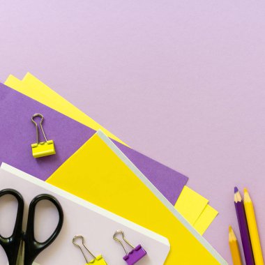 Renkli arka planda sarı ve leylak rengi okul malzemeleri var. Metin için boşluk