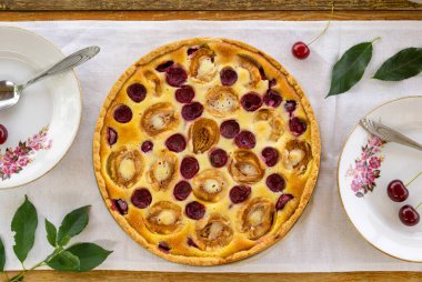 Ekşi kremalı yaz meyveli turta, kayısılar ve kirazlar ahşap bir masada.