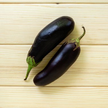 Hafif ahşap arka planda iki patlıcan, üst manzara.