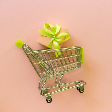 Pembe arka planda hediye kutusu olan metal alışveriş arabası. Kara Cuma konsepti