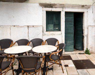 Bir Kafeterya masaları boş, eski yeşil ahşap kapı Cres (Hırvatistan) baharda açın.