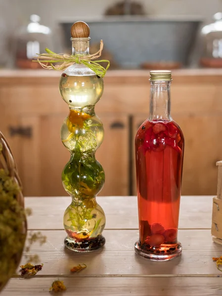 Two bottles with red and green content standing on a wooden table