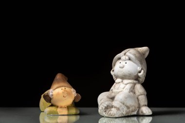 Oturma ve yansıtıcı bir yüzey, siyah arka plan üzerinde yalan cüceler küçük figürler