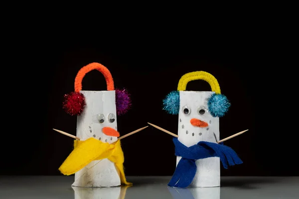 Two figures of snowmen made of toilet paper rolls by a child, black background — Stock Image Two Figures Snowmen Made Toilet Paper Rolls Child Black Background Stock Picture