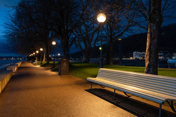 White park benches in a park in Bregenz after sunset