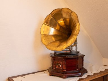 Eski bir gramofon masanın üzerinde duruyor, beyaz duvar