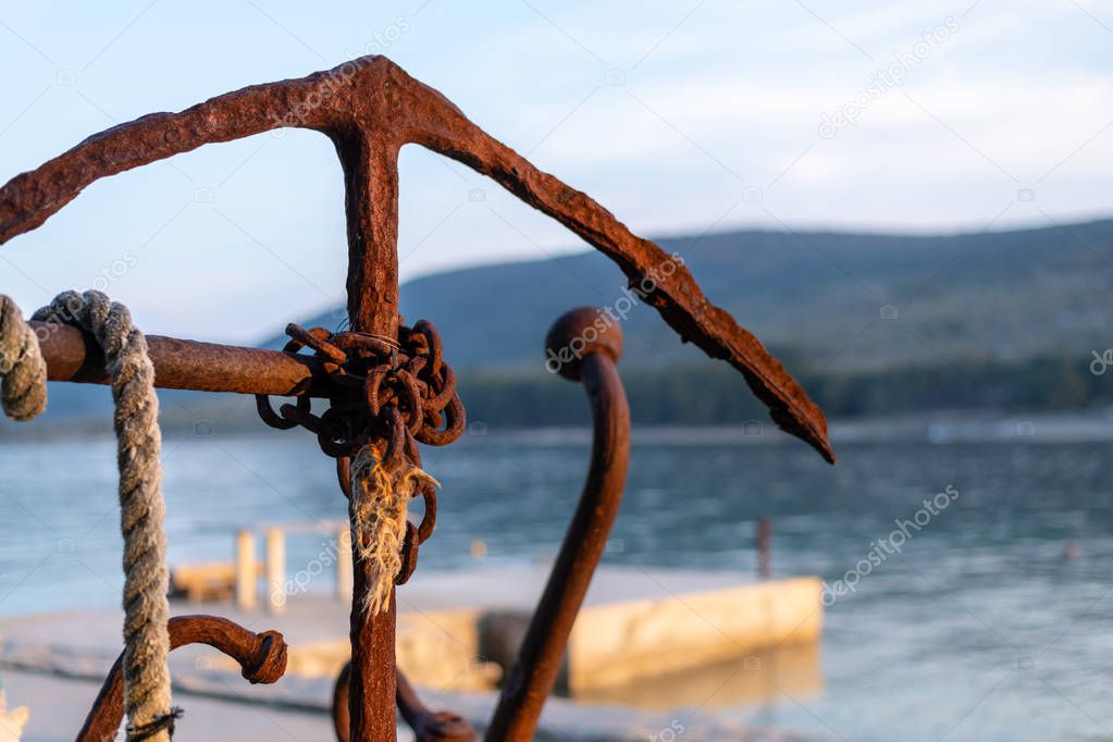 rusty old anchor with rope in the evening sun