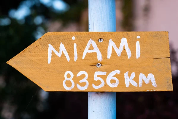 yellow sign with white font which points to Miami