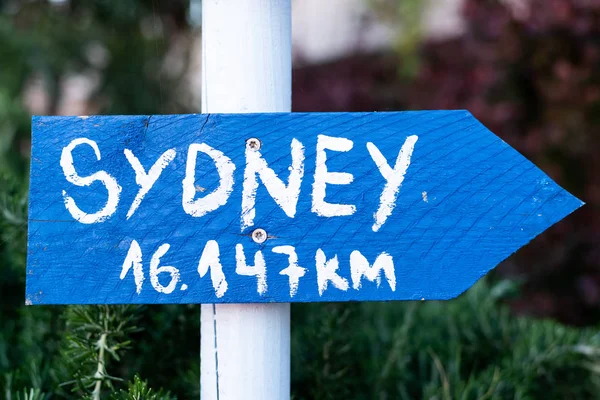 blue sign with white font which points to Sydney