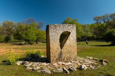 bir çayır üzerinde duran taştan yapılmış modern anıt