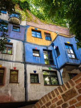 Viyana, Avusturya - 25 Haziran 2020: Güneşli bir yaz gününde Hundertwasser Haus. Bu ev düz çizgilerden, renkli resimlerden ve yoğun yeşillikten dolayı dünyaca ünlü oldu..