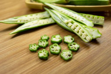 Quiabo, bamya ya da ahşap arka plandaki kadın parmakları..