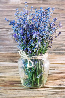 Lavanta bir ahşap arka plan üzerine kaba bir ip ile sargılı bir boyun ile cam vazoda bir buket dikey fotoğraf